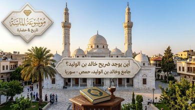 منظر خارجي لجامع خالد بن الوليد في حمص بمآذنه الشاهقة وقبابه البيضاء مع شعار موسوعة الماسة".