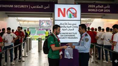 مشهد واقعي يوضح الإجراءات الأمنية المشددة عند بوابات ملاعب كأس العالم 2026، حيث يظهر رجل أمن يمنع مشجعاً من إدخال زجاجة مياه بلاستيكية، مع لافتة إرشادية واضحة باللغتين العربية والإنجليزية تؤكد قرار الفيفا بالحظر لأسباب أمنية.